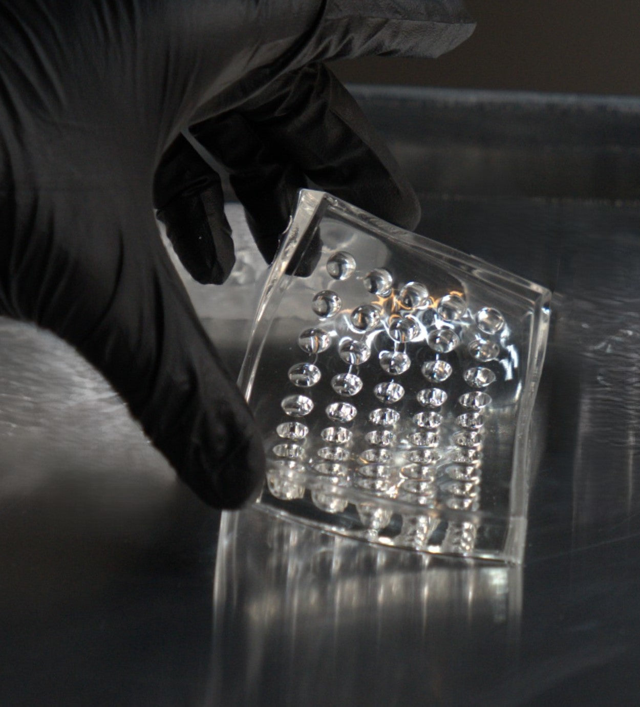 Gloved hand rinsing a cleaned cavity array mold