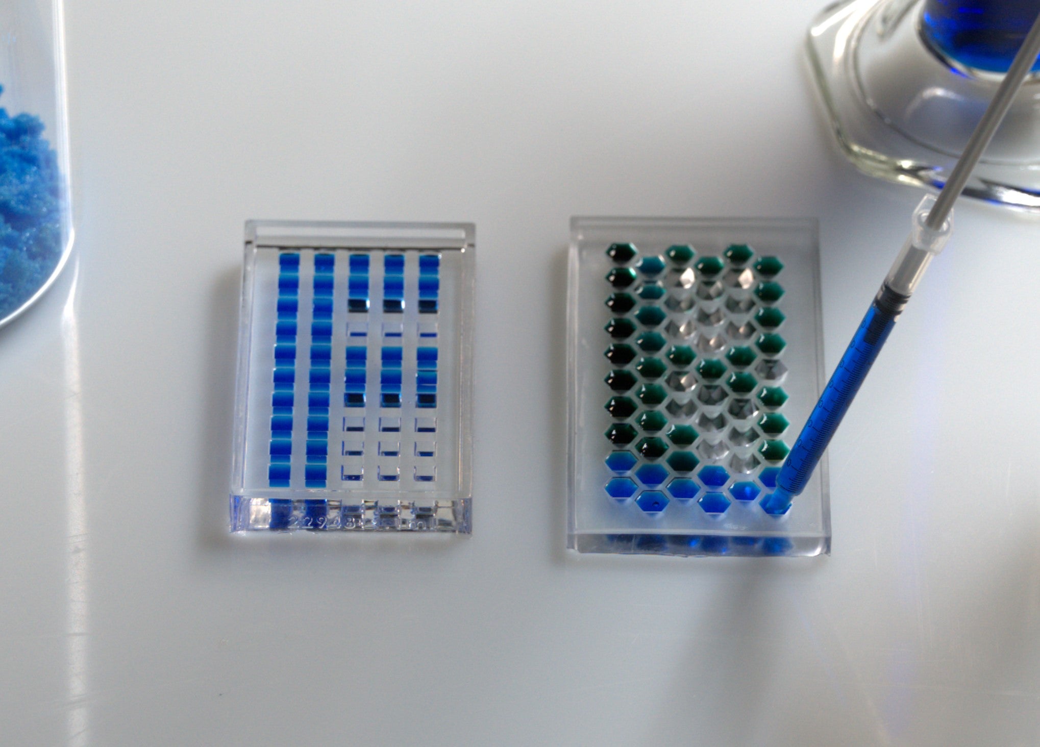 Hex and cube-well cavity array being loaded with blue dye via micropipette